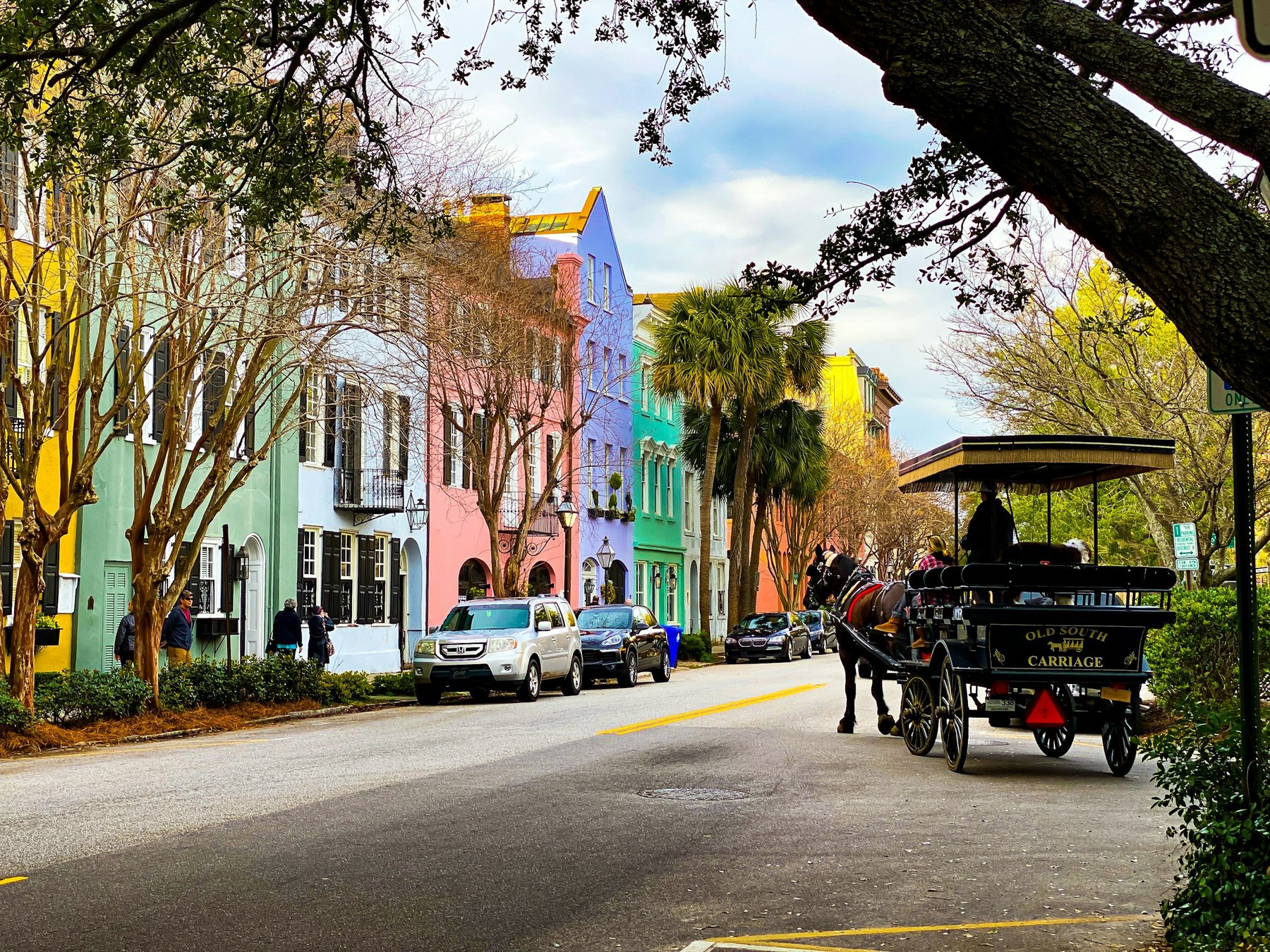 Rainbow Row in Charleston with a horse-drawn carriage passing